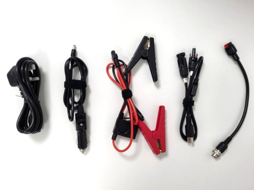 Overhead shot of accessory cables included: mains charger, car charger, crocodile clips, solar adapter cables